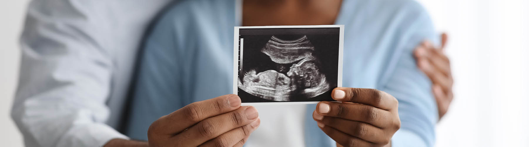 A couple holds a black and white picutre of their child's sonogram image.